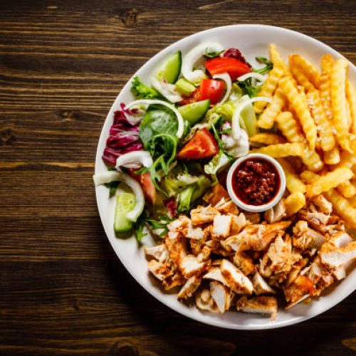 kebabs grilled meat, french fries and vegetables on wooden background